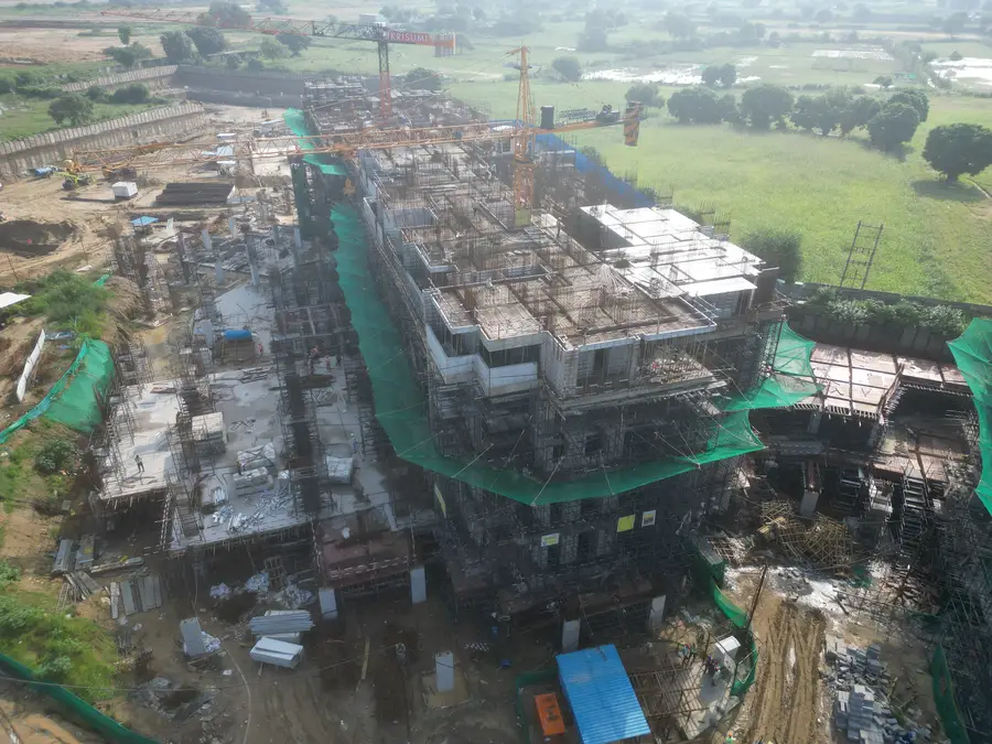 Aerial view of a tower under construction with cranes and scaffolding